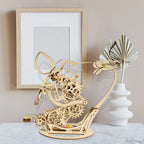 Wooden mechanical bird sculpture on a table with a framed picture DIY Puuzzle | Kinetic Hummingbird Sculpture - 3D Wooden Mechanical Puzzle Kit