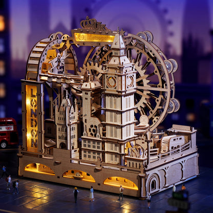 Wooden mechanical model of a clock tower with gears and lights on a blurred cityscape background