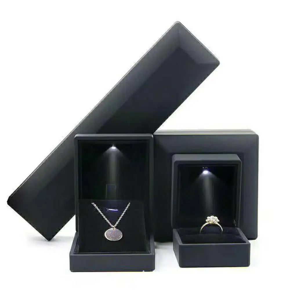 Black jewelry box with a necklace and ring inside on a white background