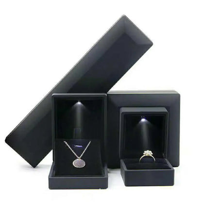 Black jewelry box with a necklace and ring inside on a white background