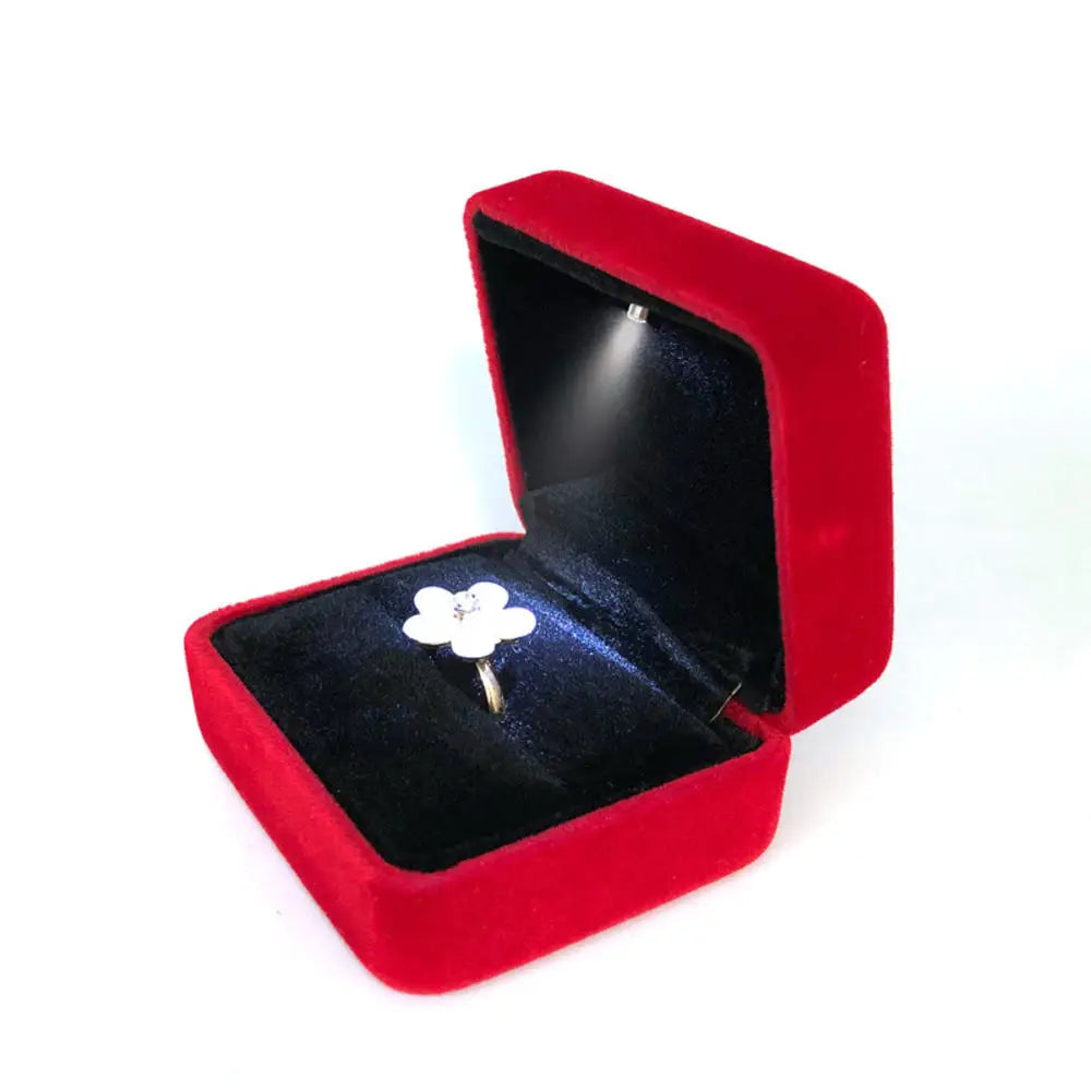 Red velvet jewelry box with a silver ring featuring a white flower design LED ring box with automatic light for engagement proposals and wedding jewelry display