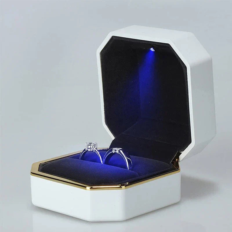 Open jewelry box with blue interior and two rings on LED ring box with automatic light for engagement proposals and wedding jewelry display
