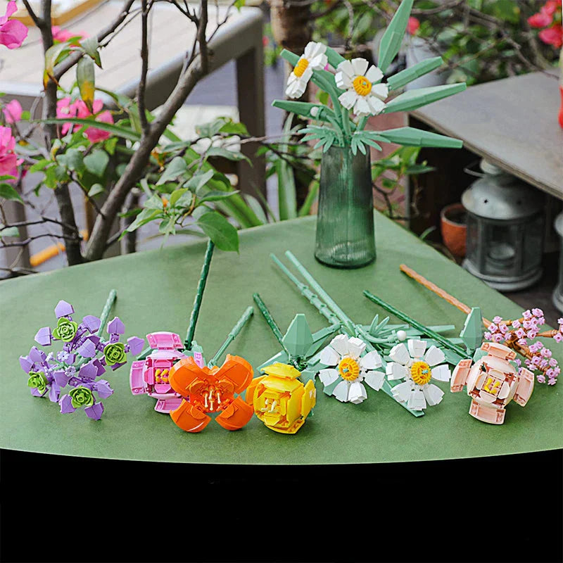 Colorful flower-shaped straws on a green surface with a blurred garden background.