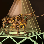 Mechanical bull model in a warm gold finish lit under a spotlight, an articulated metal animal sculpture and display centerpiece Gold
