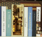 Lamplit miniature ancient street alley book nook kit slotted between real books as a glowing bookshelf display