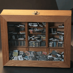 Wooden frame anxiety shelf with a glass front and brass latch displaying rows of colorful miniature books as decor