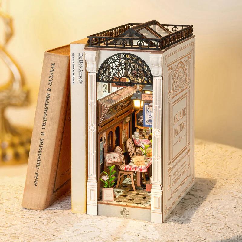 Wooden book nook diorama with an iron arch, Roman columns and a glass roof over a romantic cafe balcony scene