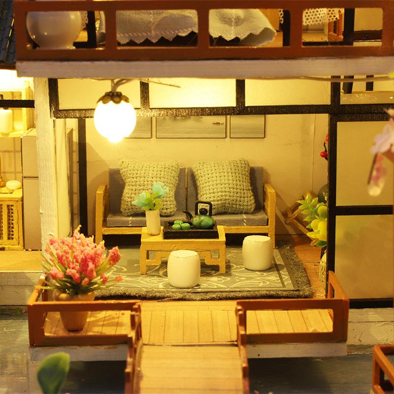 Miniature living room with a sofa, tea table, and glowing lantern, a hand-built zen dollhouse scene for shelf and desk decor