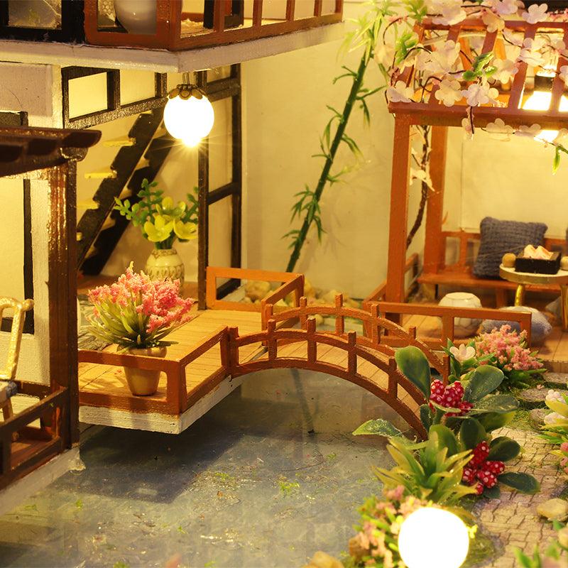 Wooden garden courtyard with an arched bridge over a pond and cherry blossom pergola, a relaxing miniature build for adults