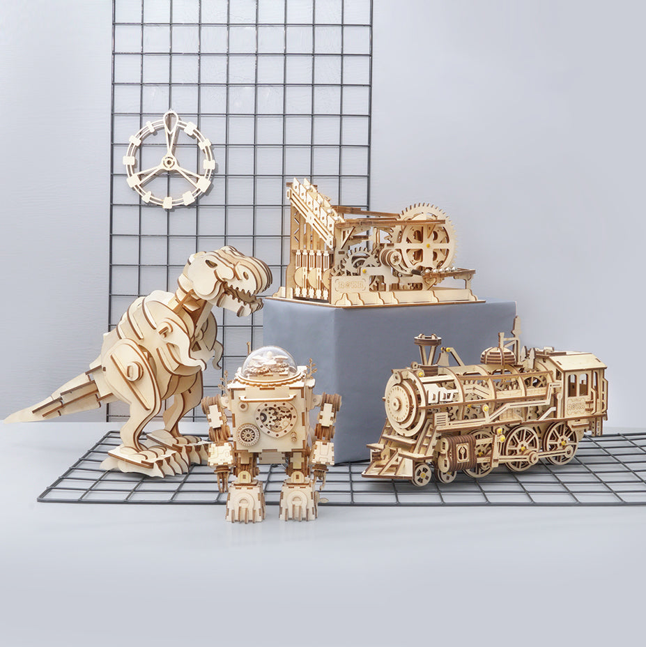 Wooden mechanical models including a dinosaur, train, and building on a grid background