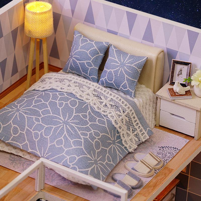 Miniature bedroom diorama with blue floral bedding and a lit tripod lamp, a 1:24 dollhouse kit for shelf and desk decor