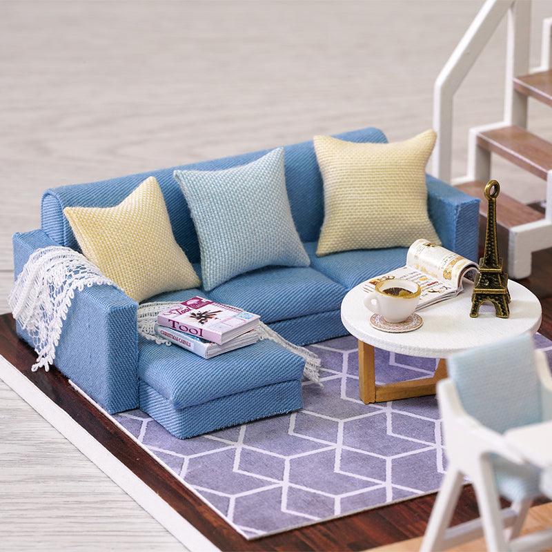 Miniature living room with a blue sofa, side table, and patterned rug, a 1:24 dollhouse kit and craft gift for ages 14 and up