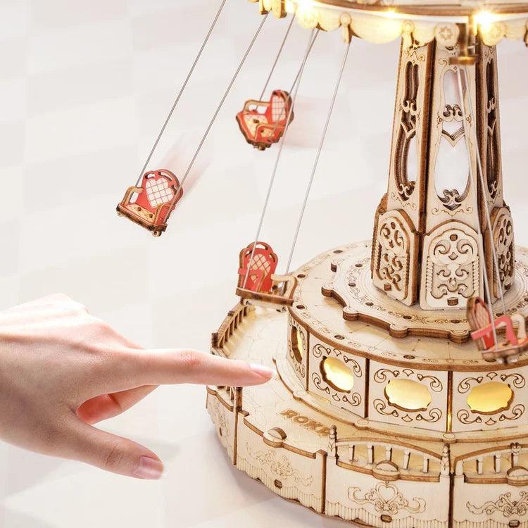 Music box carousel with red and white swing chairs that rotate around the center as the built in melody plays