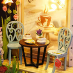 Tiny garden cafe table set with scrollwork chairs, coffee cups and blooming flowers, a cozy craft model for cat and coffee fans