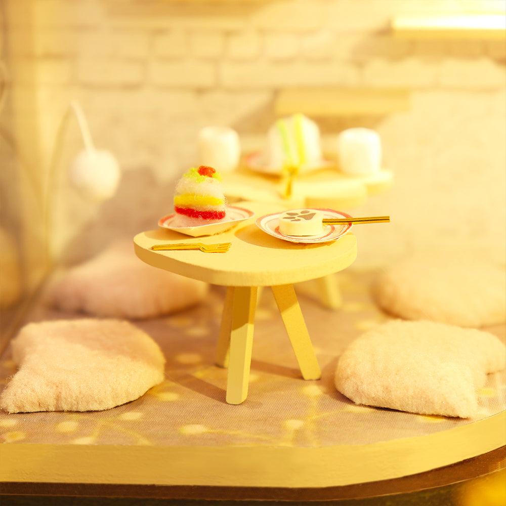 Warm LED lit cafe nook with a dessert table and soft floor cushions, a glowing miniature build for desk or bedroom decor