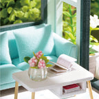 Green miniature living room with a mint sofa and armchair, part of a 1:24 scale DIY apartment dollhouse kit for adult crafters