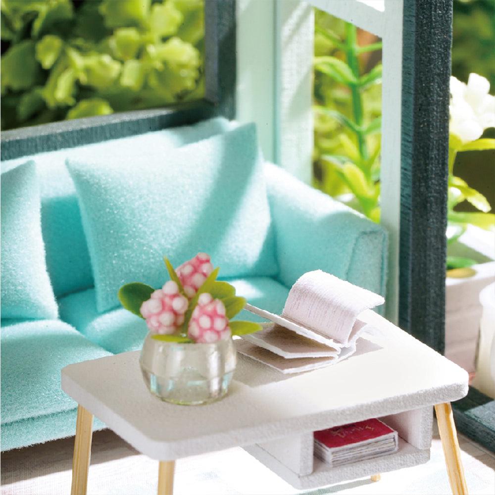 Green miniature living room with a mint sofa and armchair, part of a 1:24 scale DIY apartment dollhouse kit for adult crafters