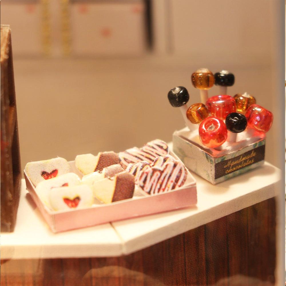 Miniature sweet shop counter with tiny lollipops and chocolates, a hands on laser cut craft kit for miniature lovers