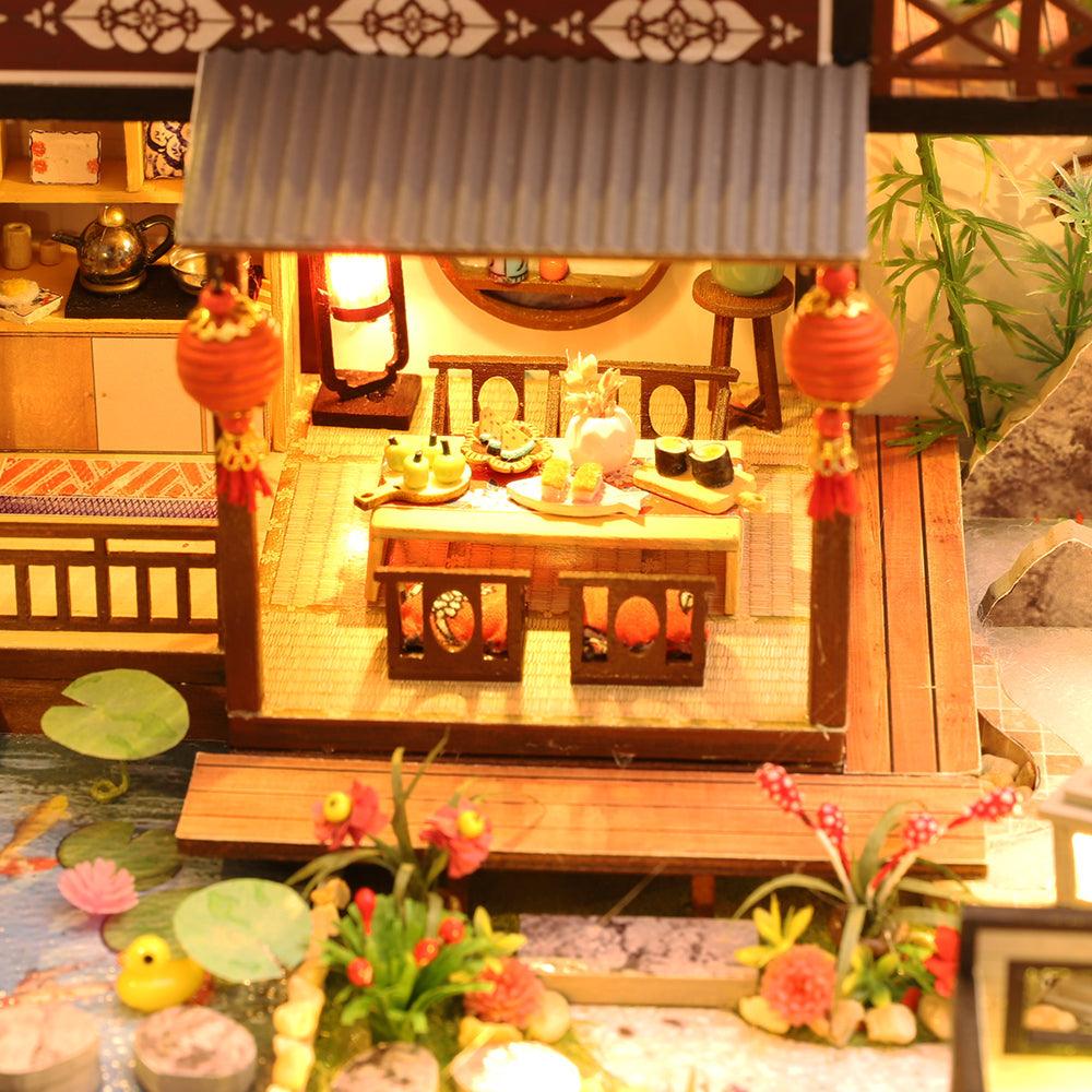 Miniature dollhouse patio with an outdoor dining set beside a lily pond, a detailed diorama gift for dollhouse fans