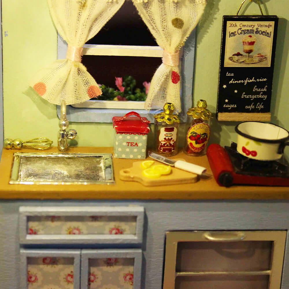 Miniature camper kitchenette with tiny jars, curtains, and a window, a detailed 1:24 caravan build for model hobbyists