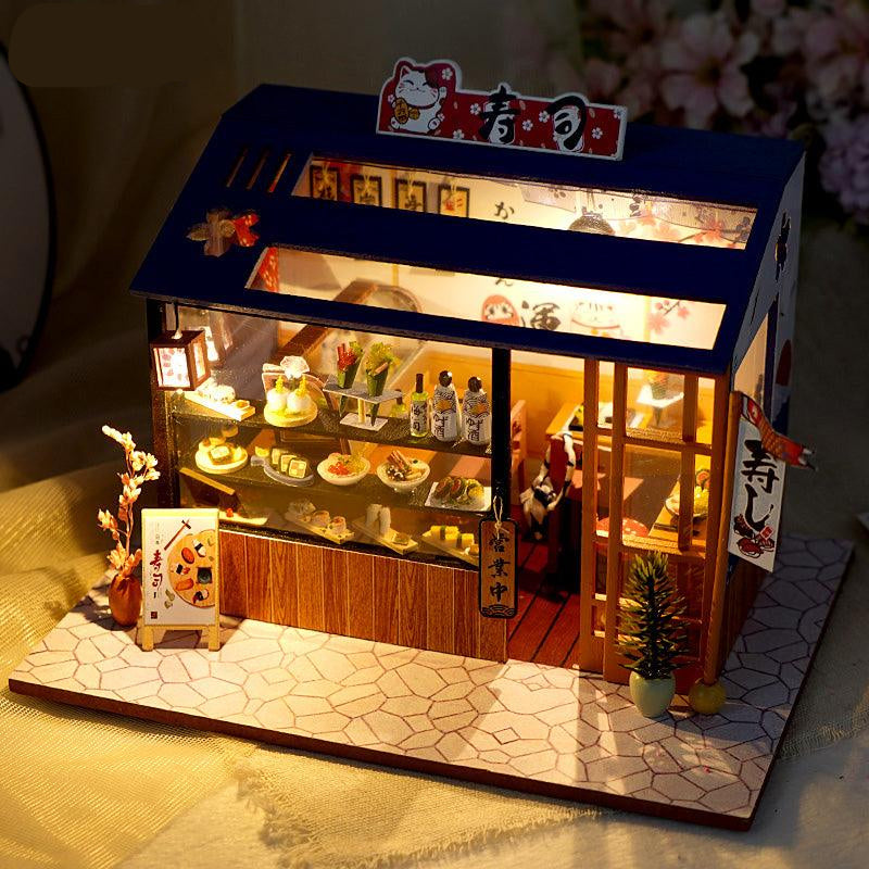 LED lit miniature sushi bar dollhouse glowing on a desk as handmade shelf decor and a relaxing adult craft hobby build Cute sushi