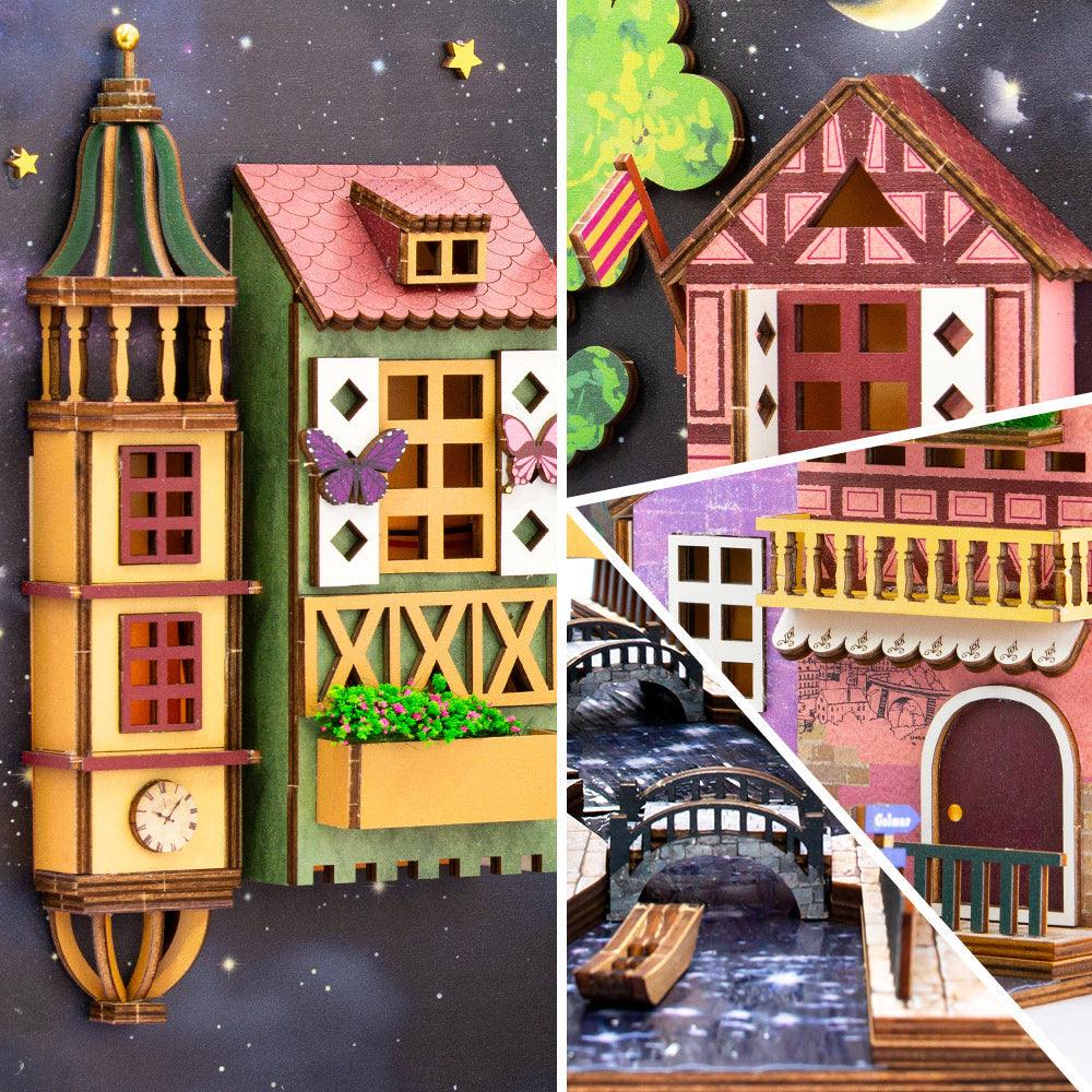 Miniature clock tower and flower box beside a Colmar canal with stone bridges, warm lit book nook diorama for shelves