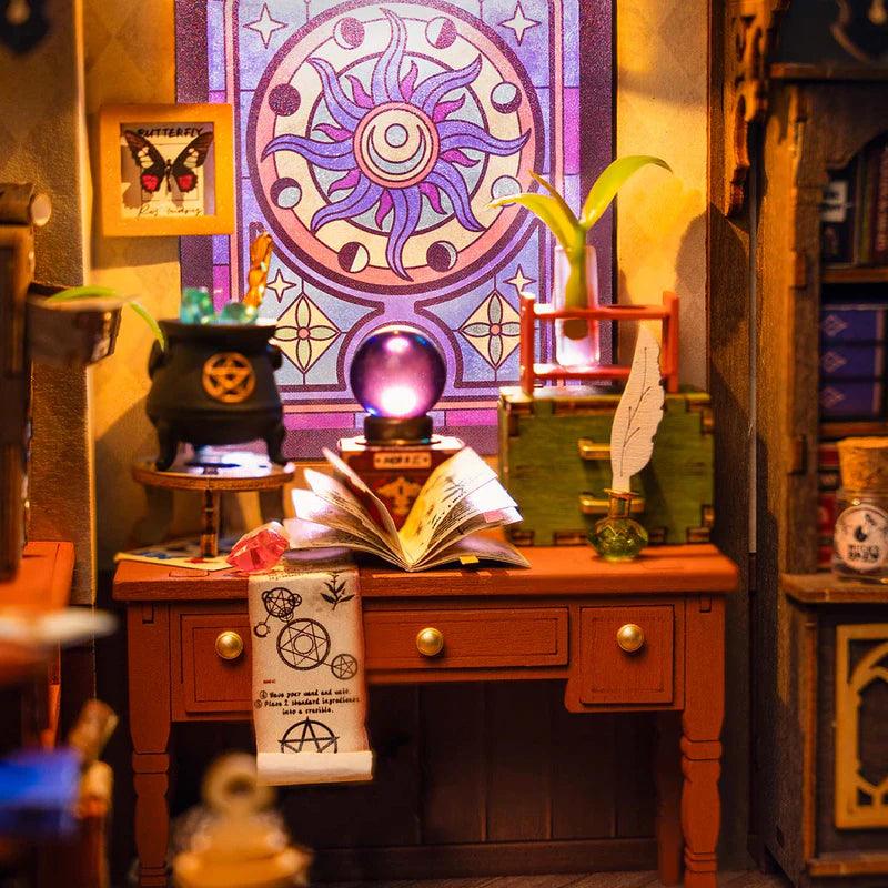 Miniature wizard study with a stained glass window and warm LED lighting over the desk, magic themed dollhouse kit for hobbyists