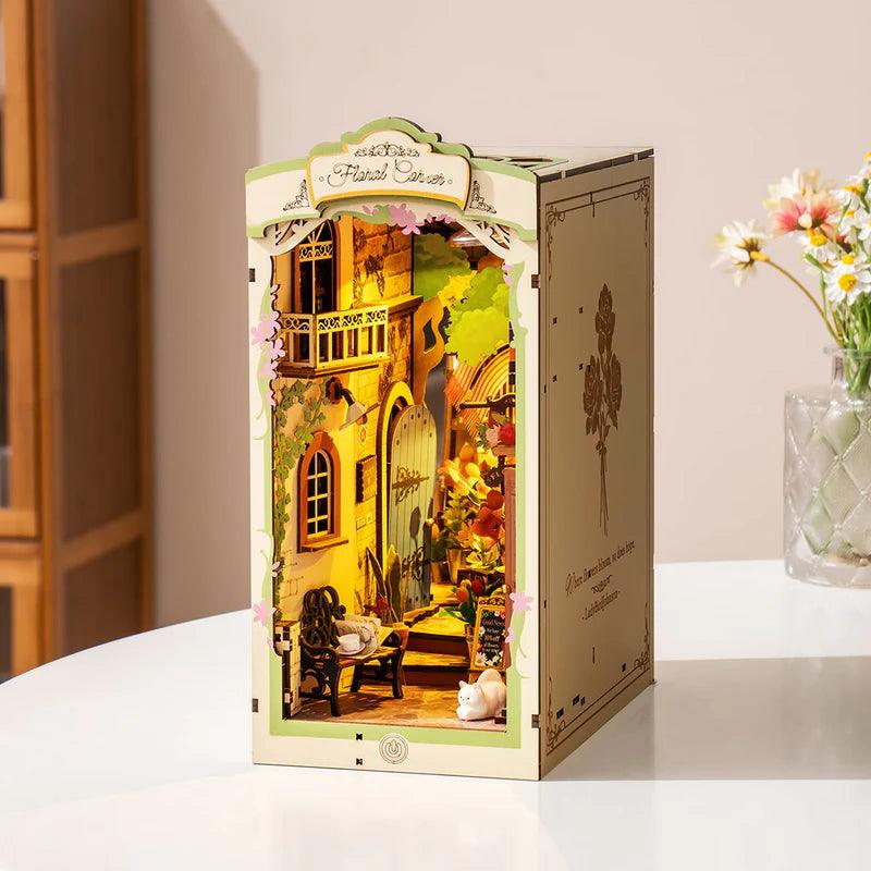 Assembled floral corner book nook on a desk with an engraved side panel, a miniature flower shop display for shelves