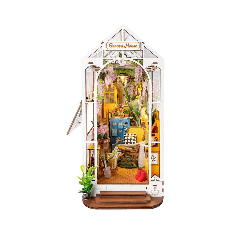 DIY book nook kit that builds the Holiday Garden House, a lit miniature bookshelf insert glowing between books