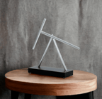 Swinging sticks kinetic sculpture as modern office decor and a conference table centerpiece on a Black display base