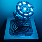 Illuminated arc reactor face with concentric blue LED rings, a Tony Stark chest lamp replica and ambient night light for a desk