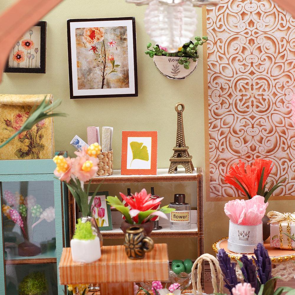 Miniature florist decor with framed botanical prints, tiny vases, and blooms, a handcrafted room box diorama for shelves