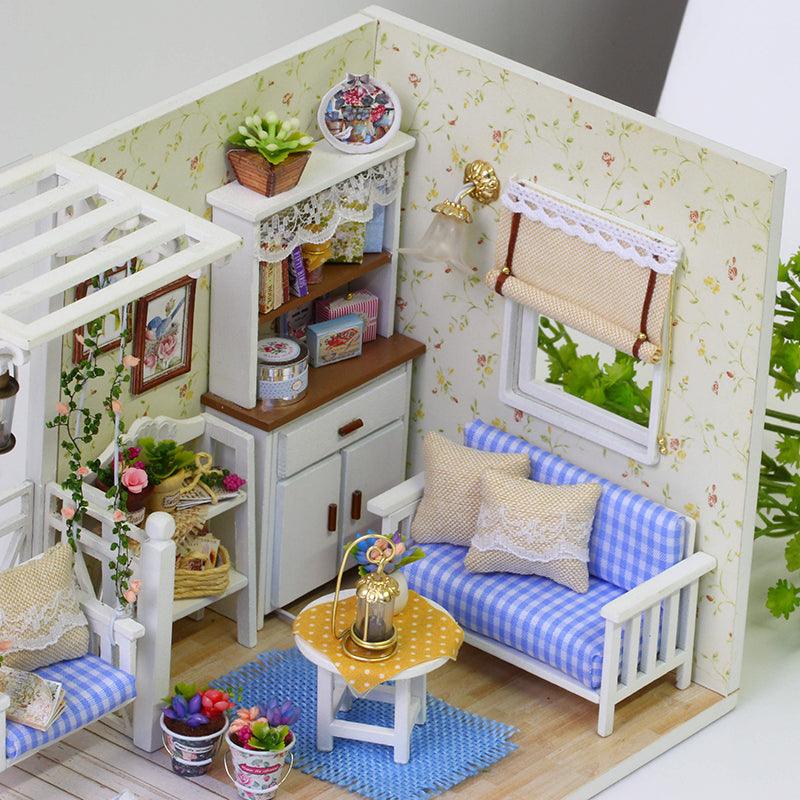 Blue gingham miniature sofa and white display cabinet set against floral wallpaper in a handmade cottage living room craft kit