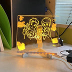 Light up LED drawing board for kids glowing with a colorful family doodle on an adjustable stand for screen-free art