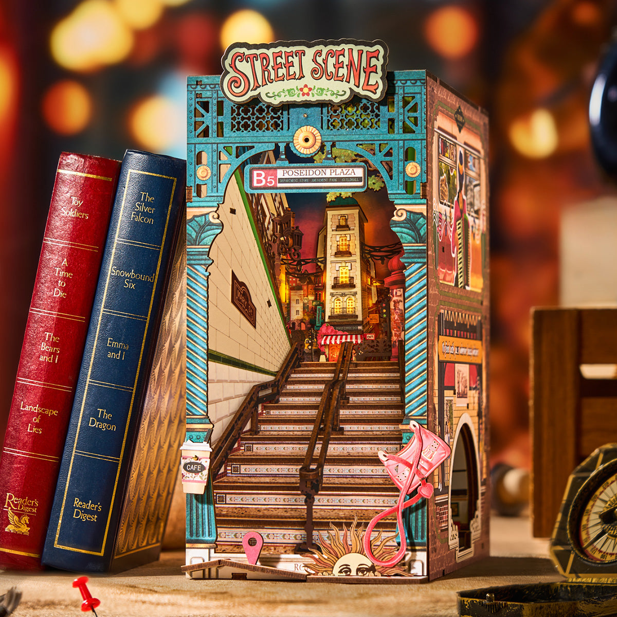 Illuminated book nook shelf insert with glowing street lamps and lit shopfronts creating a warm miniature city scene