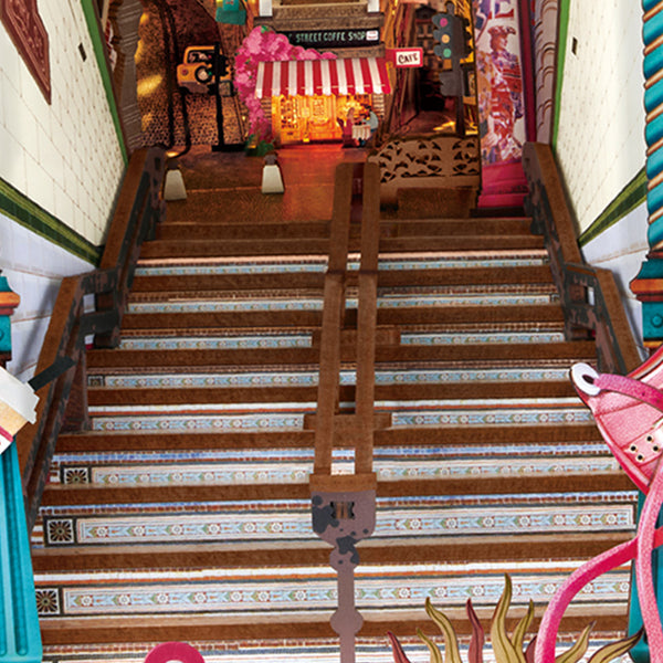 Narrow staircase descending into the street scene book nook past decorative tiles toward a colorful lit storefront