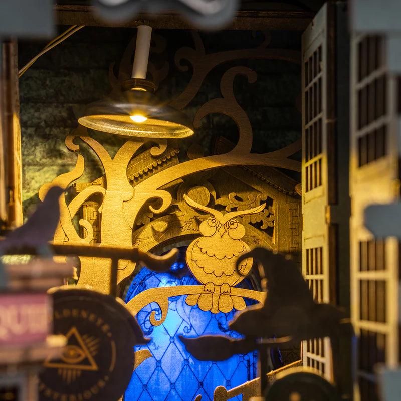 Ornate golden owl archway and hanging lantern glowing over a blue stained glass window in the fantasy book nook kit