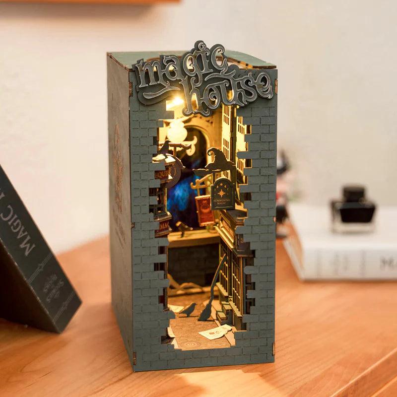 Miniature magic shop book nook lit on a desk beside books, a birthday or Christmas gift for book lovers and fantasy fans