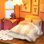 Warmly lit bedroom scene with a knit bed set and framed deer wall art in a hands on miniature dollhouse kit for crafters