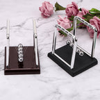 Newton's cradle desk toy shown in both black and red base finishes with polished steel balls for home or office decor (fits SKU_1748792312012_64, SKU_1748792312012_490)