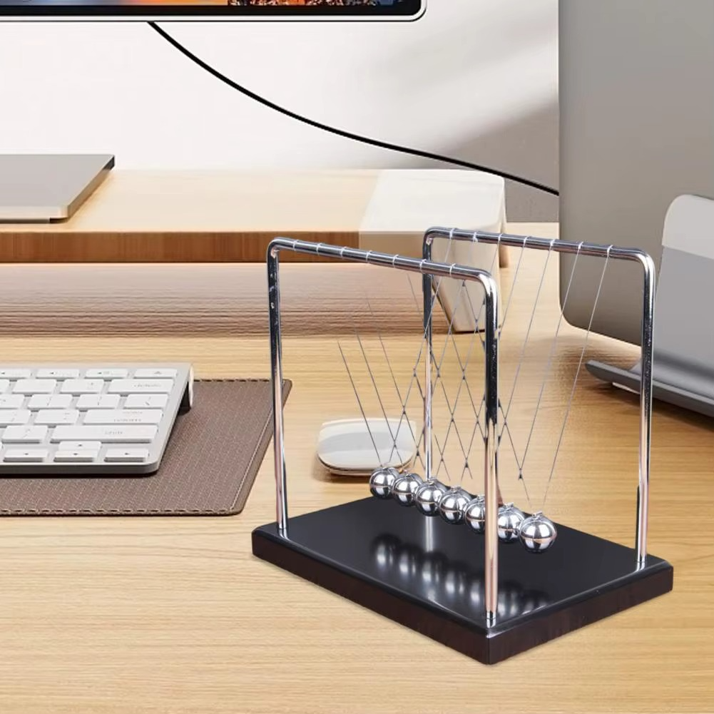 Newton's cradle on a black base set beside a keyboard as a modern office desk accessory and calming fidget for focus (fits SKU_1748792312012_490)