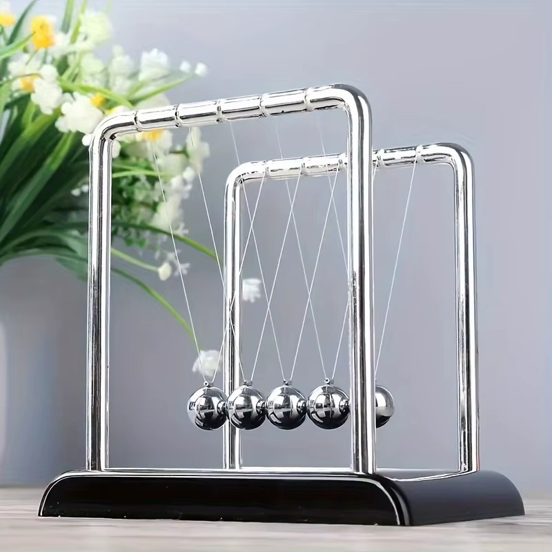 Newton's cradle with a black base and steel balls as a kinetic home shelf accent for a study, den, or reading nook (fits SKU_1748792312012_491)