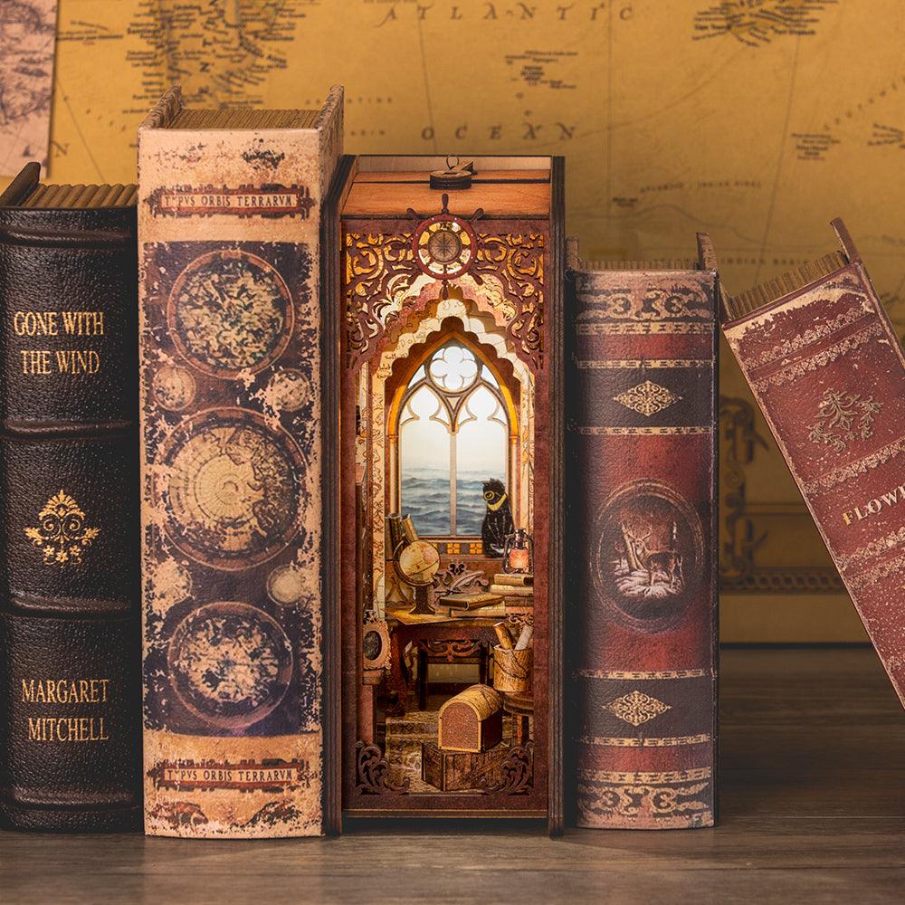 Sailing Memory book nook kit lit between real books, a maritime tavern diorama with a sea-view window for shelves