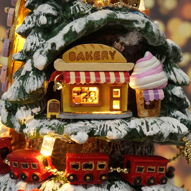 Glowing miniature bakery shop tucked in a snowy tree with a red train below, a festive Christmas building kit for adult crafters