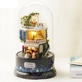 Starry miniature dollhouse kit with warm LED lights glowing under a glass dome on a rotating music box base