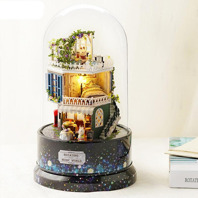 Starry miniature dollhouse kit with warm LED lights glowing under a glass dome on a rotating music box base