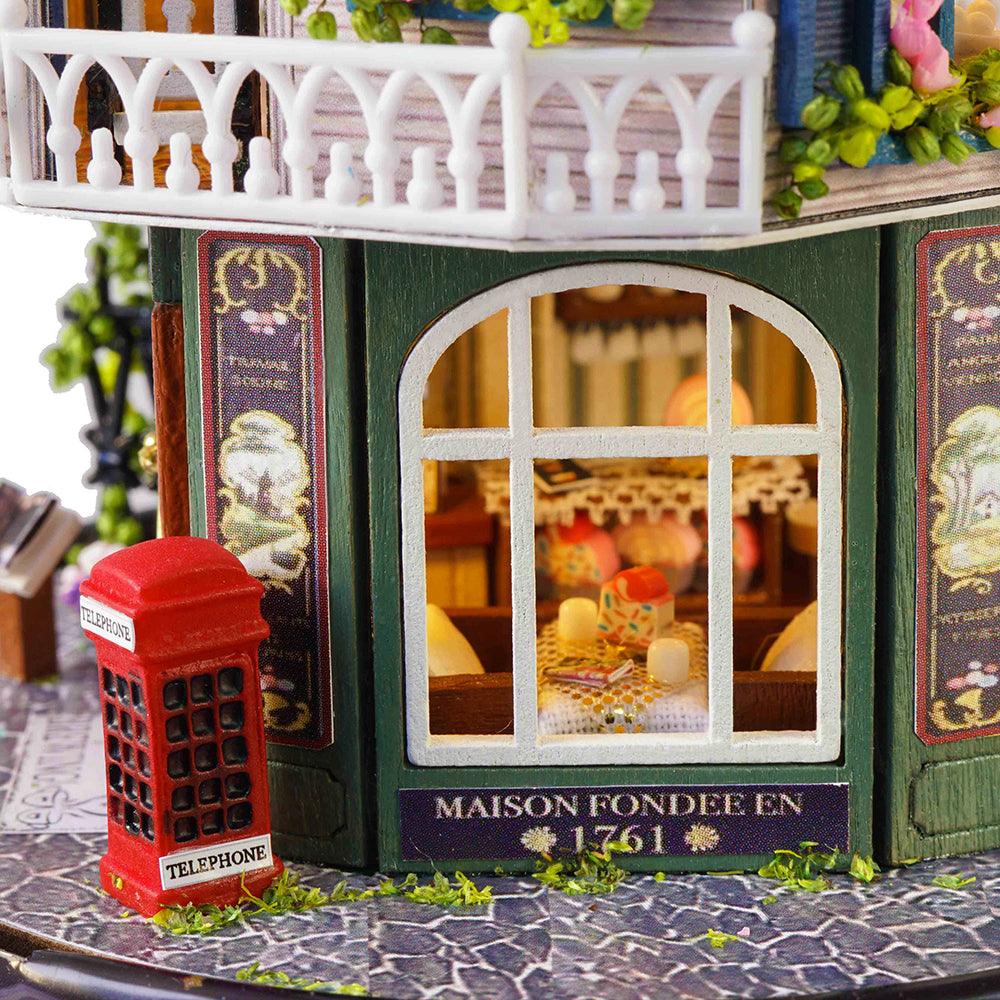Vintage bakery storefront with a red telephone box and arched window in a furnished miniature dollhouse room kit