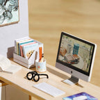 Miniature home office desk with a computer, tiny books and eyeglasses in a bright furnished 1:24 dollhouse room