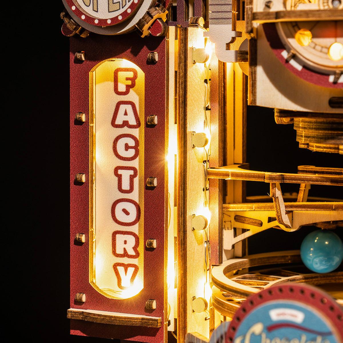 Glowing factory marquee sign on a wooden marble machine, a steampunk gravity track model and conversation starter for a desk