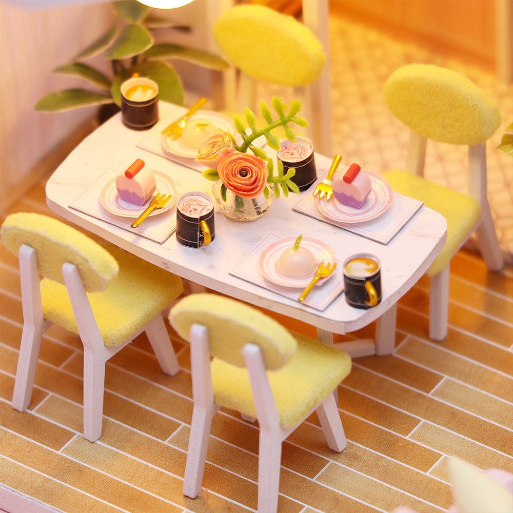 Tiny furnished dining room with a set table, dessert plates and pastel chairs, a miniature house craft kit for adults